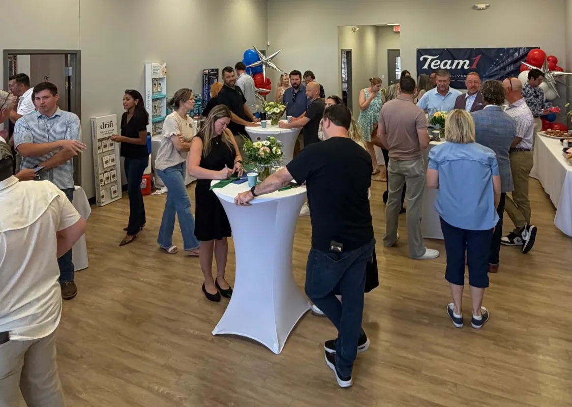 Guests mingling around high-top tables at the reception inside the Team 1 office