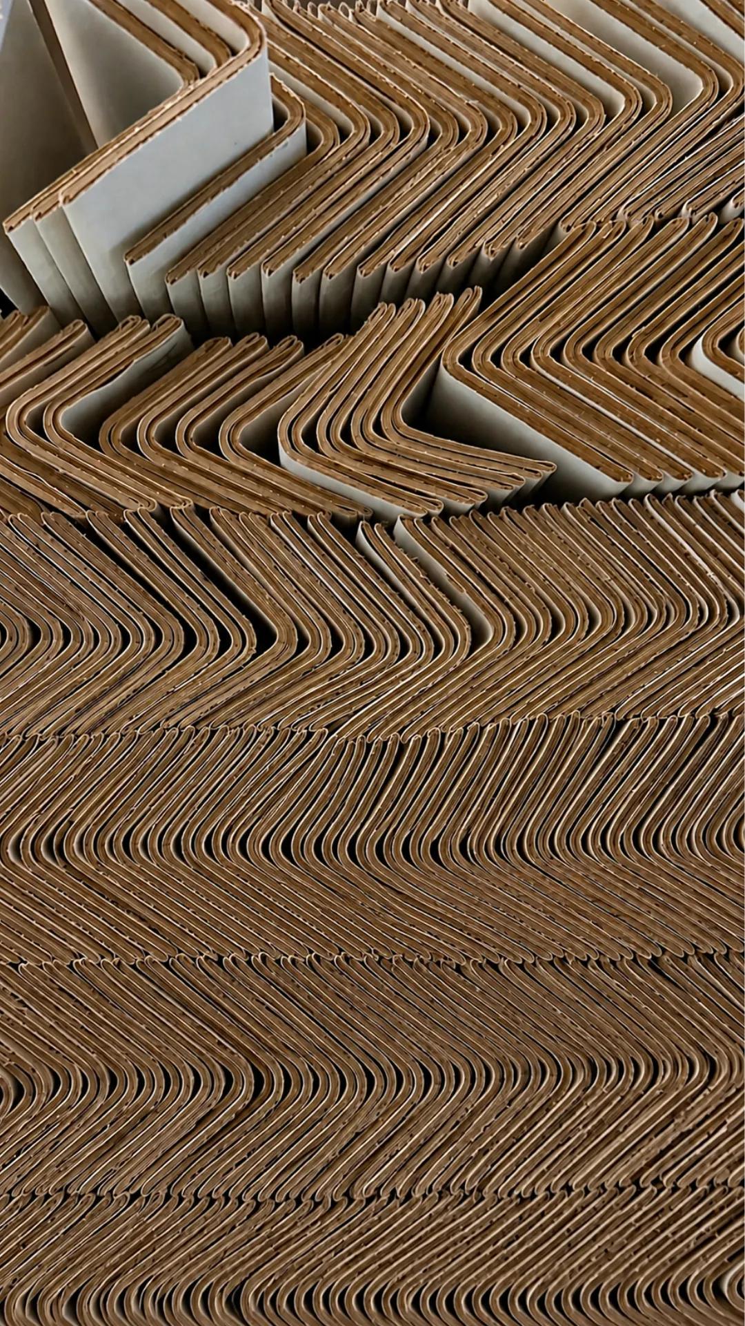Rows of cardboard corner protectors stacked in a zigzag pattern