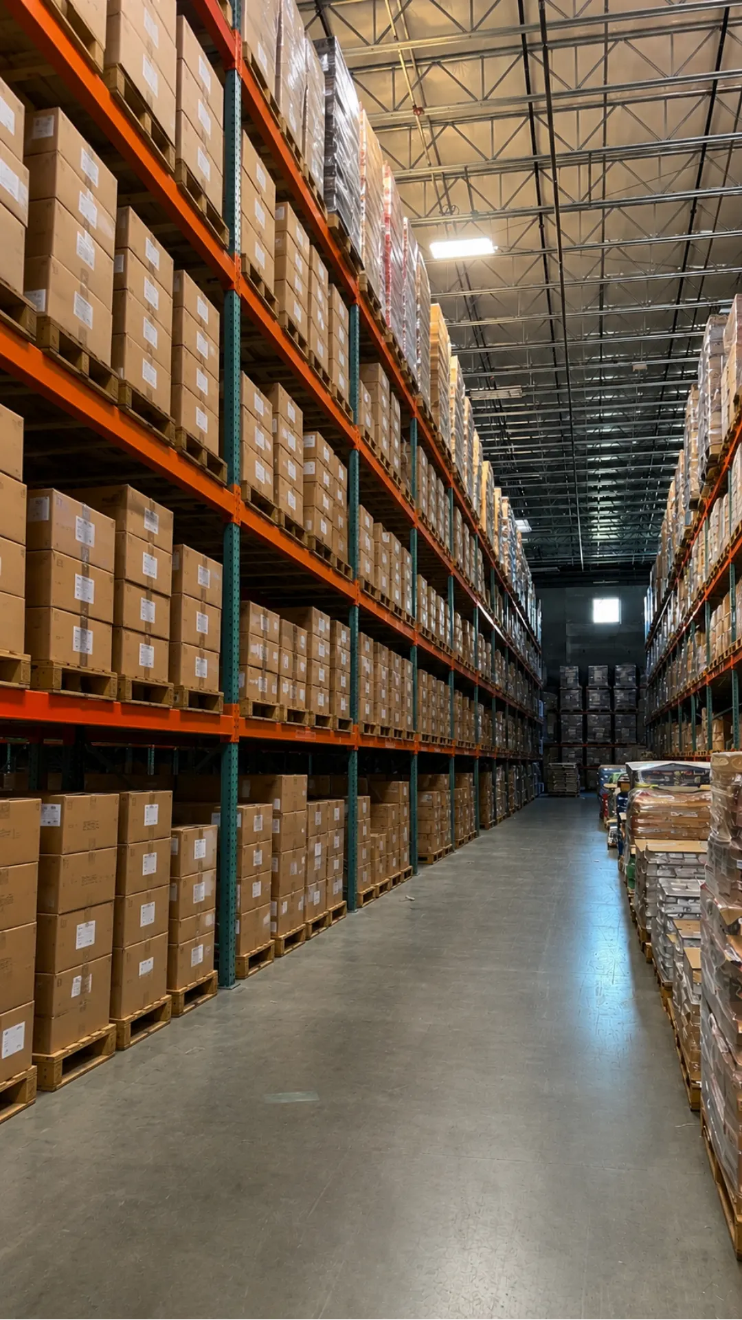 Tall pallet racking aisle stocked floor to ceiling with labeled cartons